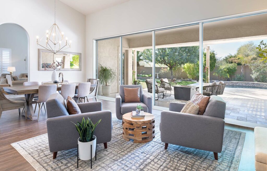 A large sliding glass door connects an indoor seating and dining area to an outdoor seating area with a fire pit.