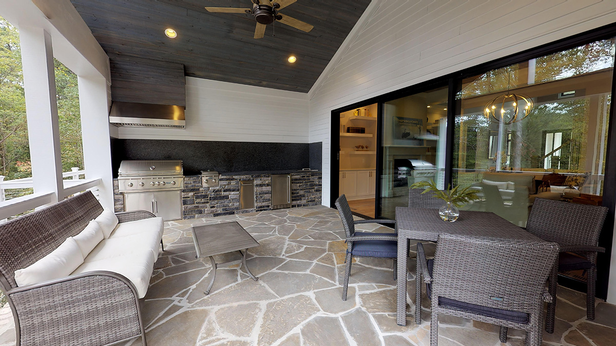 A patio mixes materials with a stone-faced outdoor kitchen, stone patio, and wood paneling around a massive sliding door.
